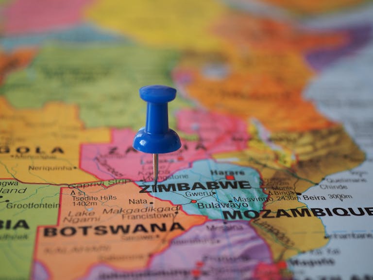 A blue pushpin marks Zimbabwe on a colorful close-up map highlighting its geographical position.