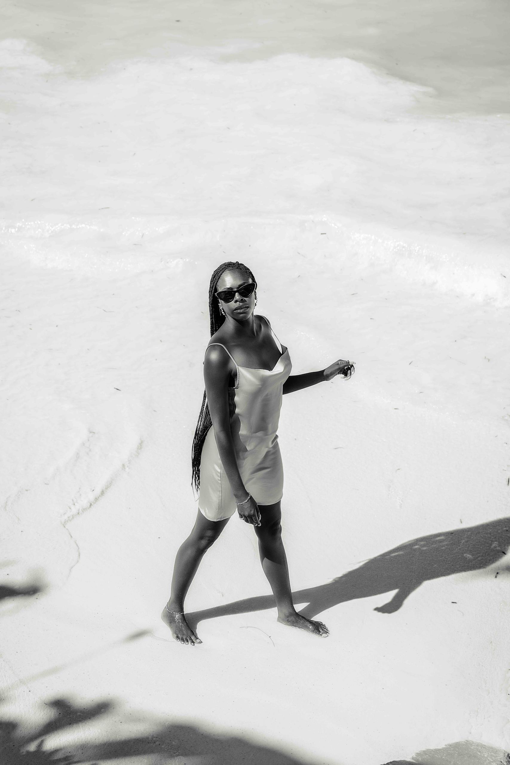 Elegant woman in sunglasses posing on a sandy beach in Zanzibar, Tanzania.