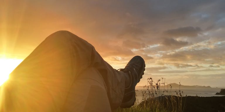A person relaxes at sunset, capturing a scenic mountain and lake view.