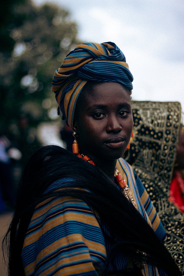 A woman in Zaria, Nigeria, wearing vibrant traditional clothing and jewelry, showcasing cultural heritage.