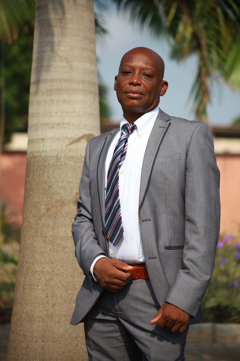 Elegant businessman in suit under palm trees, showcasing professionalism and confidence.