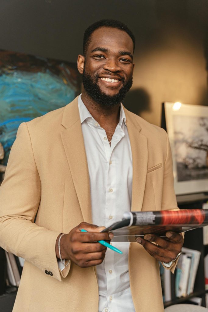 Smiling black businessman holding documents in a modern office setting.