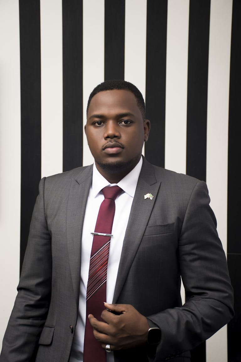 Business portrait of a black man wearing formal attire against a striped background.