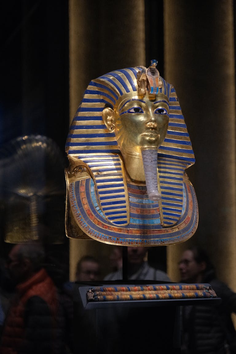 The iconic gold and blue mask of Pharaoh Tutankhamun in a museum exhibit.