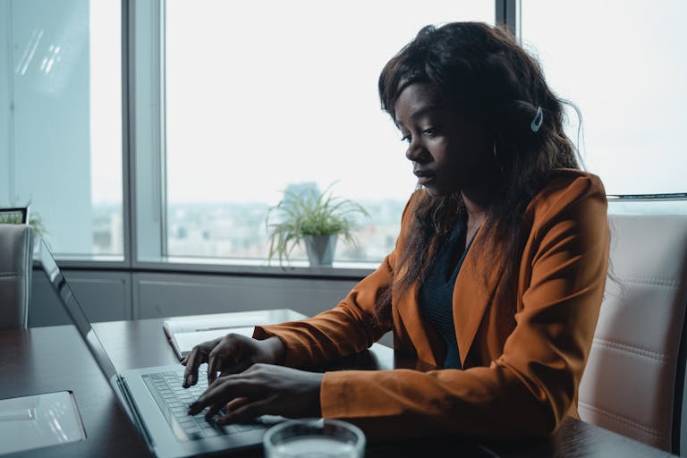 African American woman typing on laptop in a modern office setting.