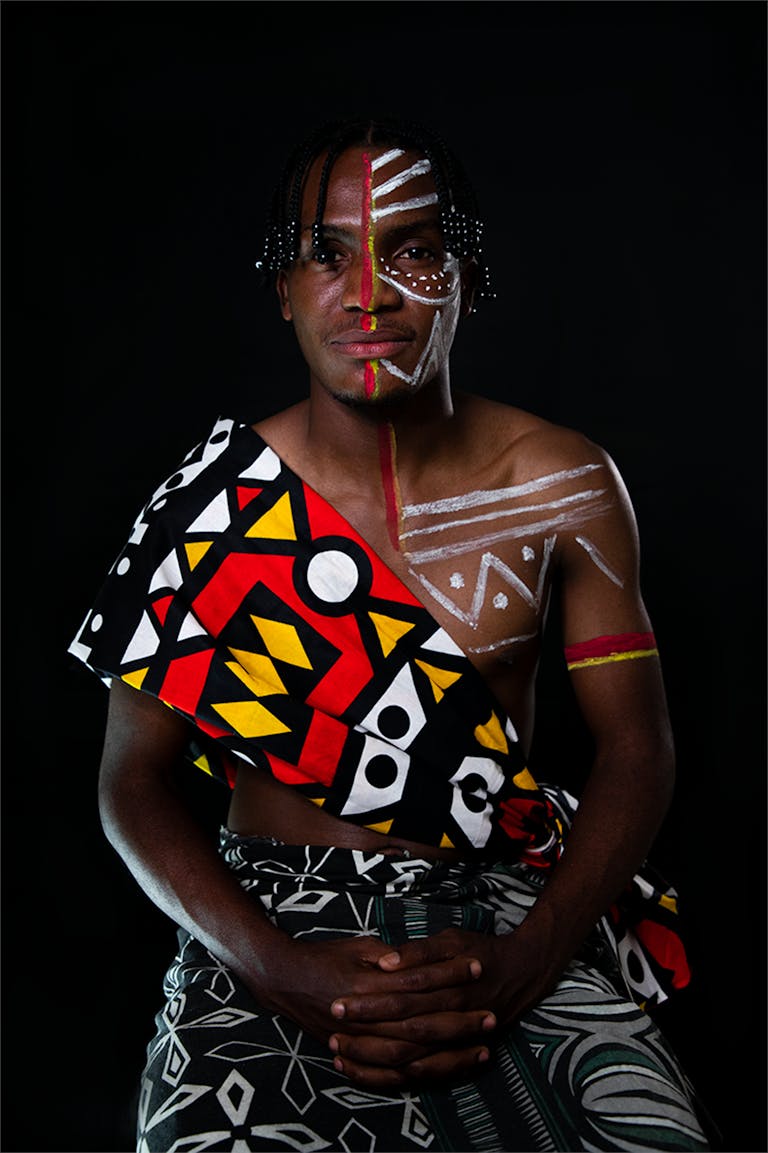 Colorful tribal portrait of a man with face paint and traditional attire from Angola.