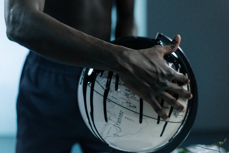 A hand holding a globe dripping with oil, symbolizing pollution and fossil fuels.
